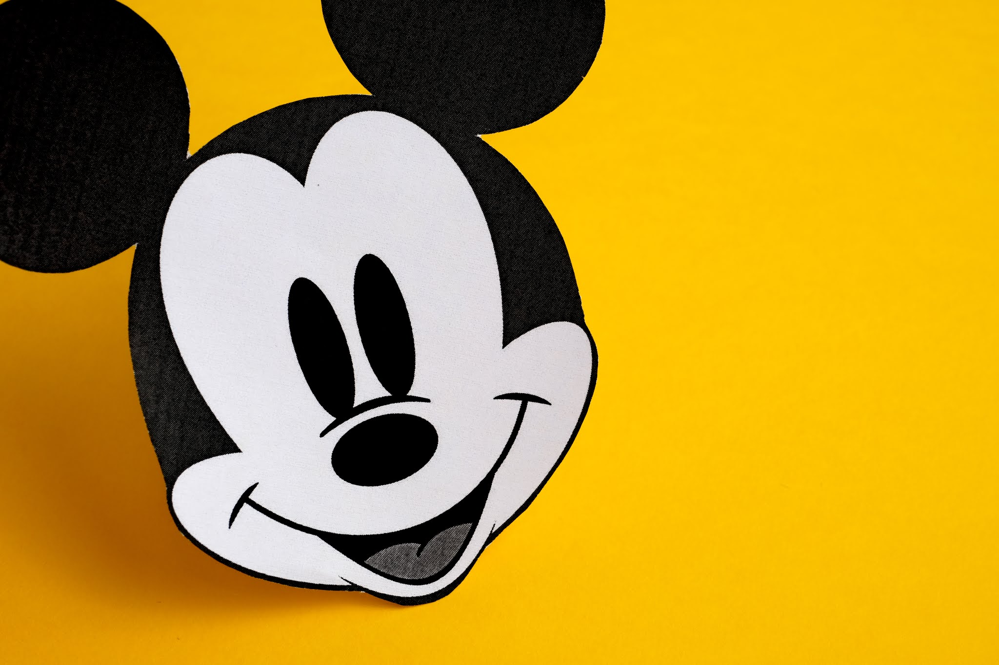 Header image: Black and white face of Mickey Mouse out of paper on a yellow background (Credit: Shutterstock.com)