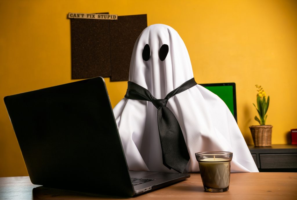 Header image: Person dressed as a ghost in a sheet and tie in front of a computer (credit: Jose Bolio / Shutterstock.com)